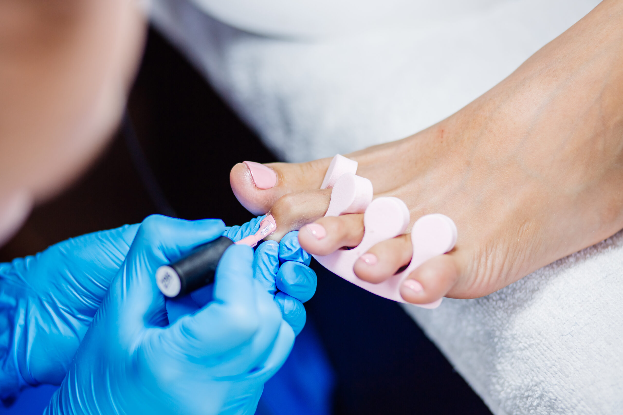 salon de pedicura en casa tratamiento para el cuidado de los pies y las unas el proceso de pedicura profesional maestro en guantes azules aplicar esmalte en gel rosa claro